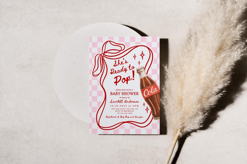 Puede incluir: Una invitaci&oacute;n a un baby shower con un dise&ntilde;o retro. La invitaci&oacute;n presenta el texto "She's Ready to Pop!" en rojo, junto con una ilustraci&oacute;n de una botella de cola. El fondo tiene un patr&oacute;n de cuadros rosas y blancos.