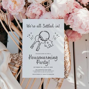 K&ouml;nnte beinhalten: Eine wei&szlig;e Karte mit schwarzem Text und einer einfachen Illustration eines Hausschl&uuml;ssels und eines Hauses. Der Text lautet "We're all settled in!" und "Please join us for a Housewarming Party!" mit Datum und Uhrzeit der Party, der Adresse und den Registrierungsinformationen.