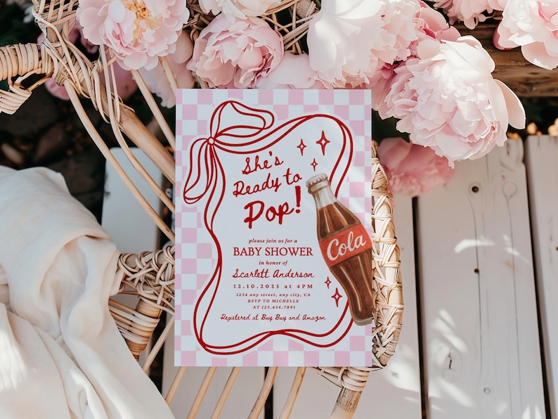 Puede incluir: Invitaci&oacute;n a un baby shower con un fondo a cuadros rosa y blanco. La invitaci&oacute;n presenta el texto "She's Ready to Pop!" y una ilustraci&oacute;n de una botella de cola. La invitaci&oacute;n est&aacute; rodeada de flores rosas.