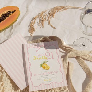 May include: A rectangular birthday invitation card with a light pink and white striped border, featuring the text She's Freshly 21, Bianca 21st Birthday, 12.10.2024 at 4PM, The Fizzy Bar, and RSVP details, decorated with a yellow lemon illustration.