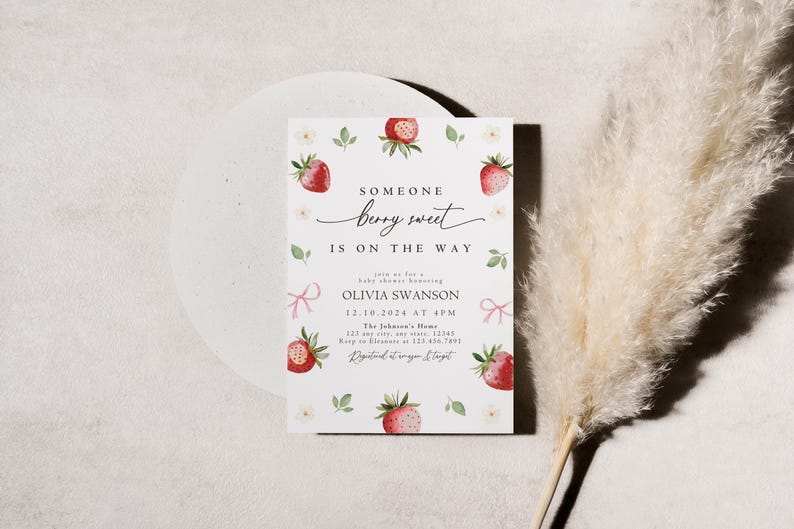 May include: A white baby shower invitation with a strawberry theme. The invitation features a watercolor illustration of strawberries and flowers. The text reads "Someone berry sweet is on the way." The invitation also includes the date, time, and location of the shower.