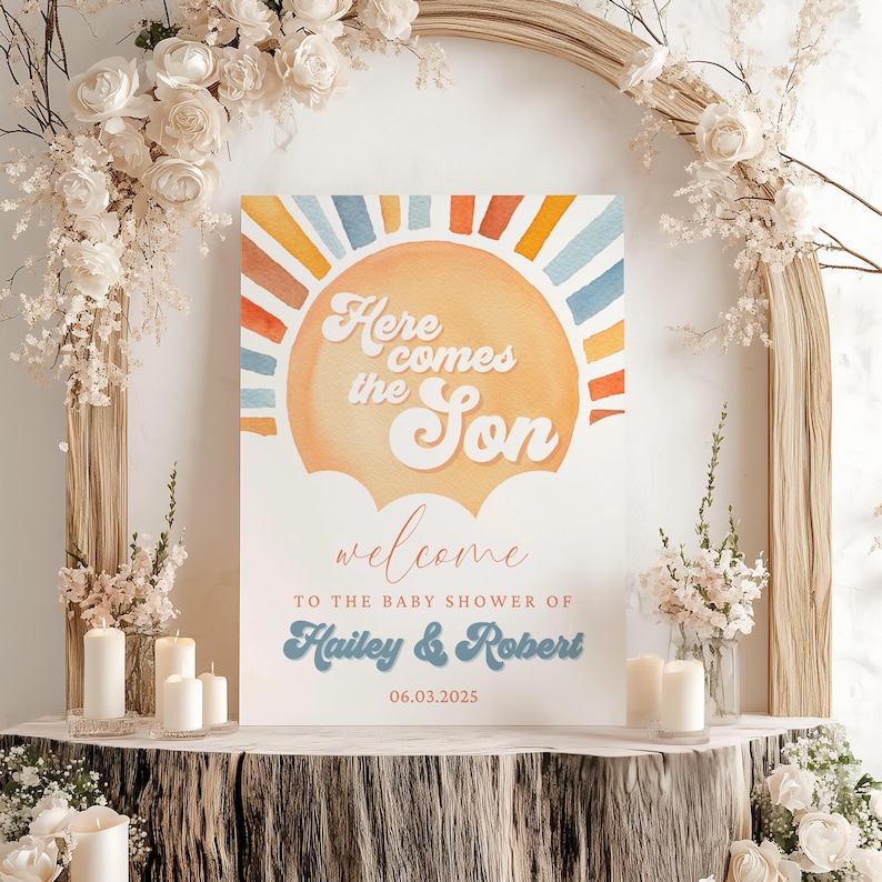 May include: A welcome sign for a baby shower with a watercolor illustration of a sun with the text "Here comes the Son" in a retro font. The sign also includes the text "Welcome to the baby shower of Hailey & Robert 06.03.2023".