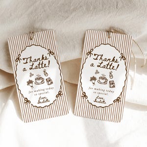 Peut inclure: Deux &eacute;tiquettes cadeaux rectangulaires &agrave; rayures verticales marron et un ovale blanc au centre. L'ovale contient le texte "Thanks a Latte!" et des illustrations de caf&eacute;. Chaque &eacute;tiquette a une ficelle attach&eacute;e.