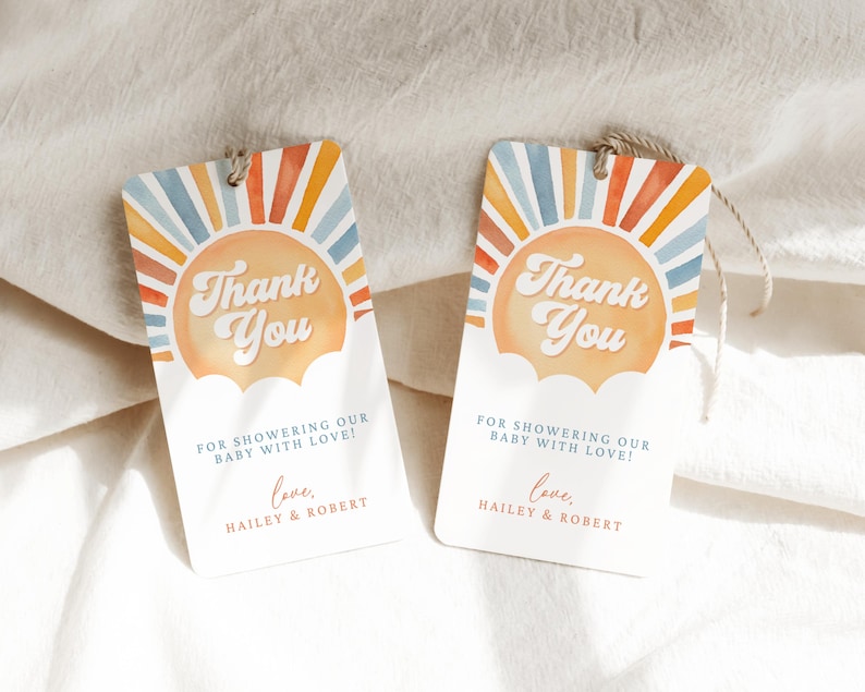 May include: Two thank you tags with a watercolor sunset design. The text on the tags reads "Thank You" with a retro font. The text below the sun says "For showering our baby with love! Love, Hailey & Robert."
