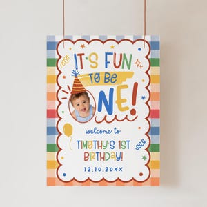 Puede incluir: Un cartel de cumplea&ntilde;os rectangular con un borde a cuadros de colores que incluye el texto IT'S FUN TO BE ONE! welcome to TIMOTHY'S 1ST BIRTHDAY! 12.10.20XX. El dise&ntilde;o incluye una foto circular de un beb&eacute; con gorro de fiesta y estrellas.