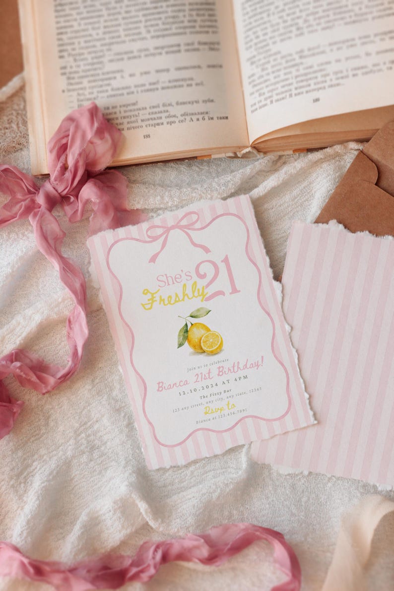 May include: A rectangular birthday invitation card with a pink and white striped border, featuring a pink bow at the top, a watercolor lemon illustration, and the text She's Freshly 21, Bianca 21st Birthday, 12.10.2024 at 4PM, The Foxy Bar, 123 any street, any state, 12345, Rsvp to Bianca at 123.456.7891.