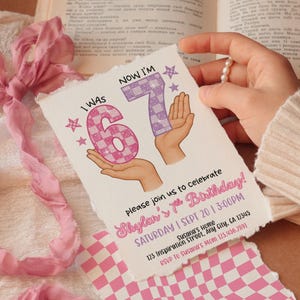 May include: A birthday invitation card with the text "I WAS 6" and "NOW I'M 7" in pink and purple checkered patterns. The card also includes the text "Skylar's 7th Birthday!" and event details. The card is held by a person.