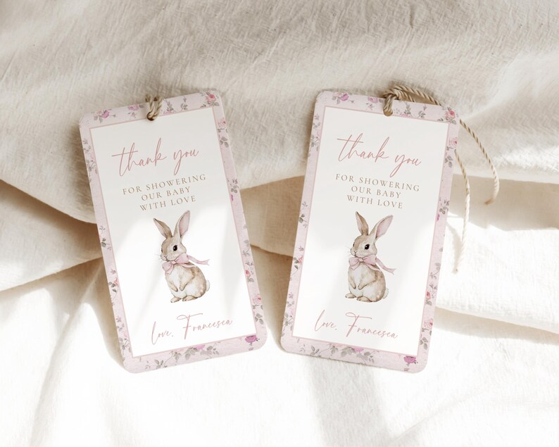 Op de afbeelding: Twee roze en witte bloemachtige bedankkaartjes met een konijnenillustratie en de tekst "Bedankt voor het verwennen van onze baby met liefde".