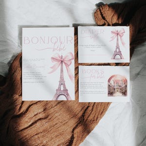 May include: A set of three baby shower invitations with a Parisian theme. The invitations are decorated with a pink bow and a watercolor illustration of the Eiffel Tower. The text on the invitations reads "Bonjour Bebe", "Diaper Raffle", and "Books for Bebe".