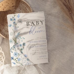 Puede incluir: Una invitaci&oacute;n a un baby shower con un dise&ntilde;o floral en tonos azules y blancos. La invitaci&oacute;n dice "Baby in Bloom" e incluye el nombre "Victoria Rivera" y la fecha "June 03, 2023".