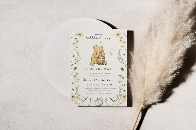 May include: Baby shower invitation featuring Winnie the Pooh with the text "our little honey IS ON THE WAY!". The invitation is decorated with floral elements and includes event details.