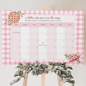 Puede incluir: Un calendario de baby shower a cuadros rosas y blancos con el texto "a little cutie pie is on the way!" y "GUESS BABY SAUNDERS DUE DATE". El calendario presenta un gr&aacute;fico de pastel y un coraz&oacute;n que marca la fecha de vencimiento.