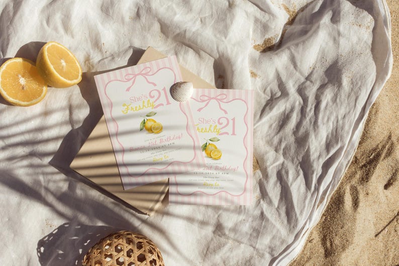 May include: Two rectangular birthday invitation cards featuring a pink striped border, a bow illustration, and yellow lemon graphics. The text reads She's Freshly 21, Birthday, and includes placeholder details. A small white seashell rests on the cards.