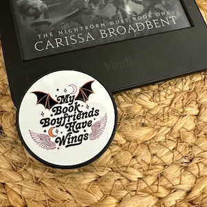 May include: A white phone grip with a black border and a design of a bat with wings and the text "My Book Boyfriends Have Wings".