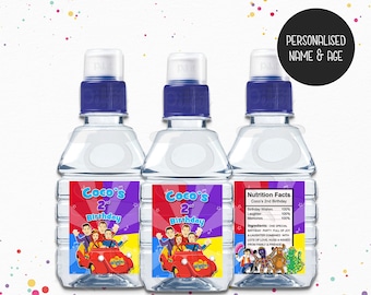 May include: Three clear plastic water bottles with blue lids and personalised labels featuring the Wiggles characters. The labels say "Coco's 2nd Birthday" and include a red car with the Wiggles characters in it. The nutrition facts label says "Birthday Wishes 100%, Laughter 100%, Memories 100%".