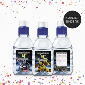 May include: Three clear plastic water bottles with blue lids and personalised labels. The labels feature a Transformers theme with the text "Nathaniel's 4th Birthday" and images of Optimus Prime and Bumblebee. The label on the right bottle includes nutrition facts with a humorous description of the ingredients for a birthday party.