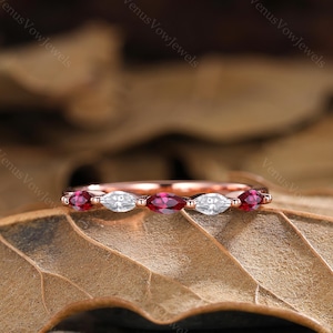May include: A delicate rose gold band with alternating marquise-shaped ruby and diamond stones.