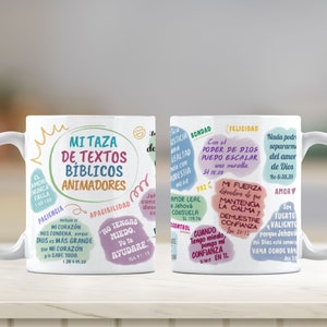 May include: Two white ceramic mugs with colorful text and illustrations. The text on the mugs includes Bible verses and inspirational quotes. The mugs are on a wooden surface.