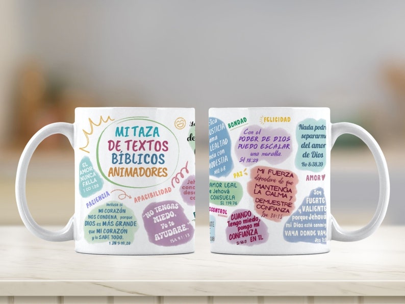 May include: Two white ceramic mugs with colorful text and illustrations. The text on the mugs includes Bible verses and inspirational quotes. The mugs are on a wooden surface.