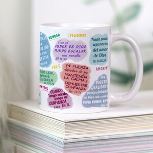 May include: White ceramic mug with a colorful design featuring inspirational quotes and bible verses. The mug has a handle and is decorated with a variety of colors, including pink, blue, green, and yellow.