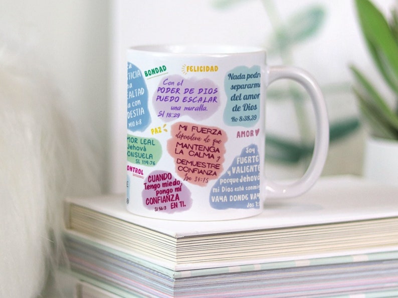 May include: White ceramic mug with a colorful design featuring inspirational quotes and bible verses. The mug has a handle and is decorated with a variety of colors, including pink, blue, green, and yellow.