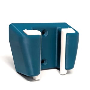 Könnte beinhalten: Ein teal-farbener Wandhalter mit weißen Akzenten. Der Halter hat eine rechteckige Form mit zwei vertikalen Schlitzen und zwei Befestigungslöchern. Das Design ist modern und minimalistisch.