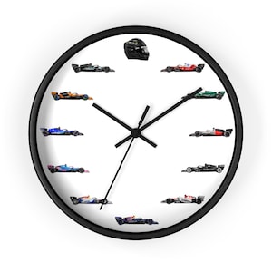 May include: A black and white wall clock featuring a racing theme. The clock face displays miniature race cars and a helmet, with black hands indicating the time. The clock has a black frame and a white background.