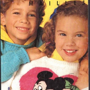 Op de afbeelding: Omslag van een vintage breipatronenboek met twee lachende kinderen. De titel "PHILDAR MAILLES" staat in roze op een gele achtergrond. De kinderen dragen truien met een Mickey en Minnie Mouse ontwerp. Nummer 215 is zichtbaar.