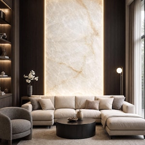 May include: A living room featuring a large beige sectional sofa, a round black coffee table, and a textured gray armchair. The wall behind the sofa is a backlit slab of cream-colored marble with brown veining, flanked by dark brown vertical wood slats.