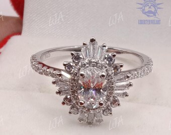 May include: A silver ring with an oval-cut center stone surrounded by smaller, baguette-cut stones in a sunburst design. The band is encrusted with small, round stones. The ring is set against a white background.
