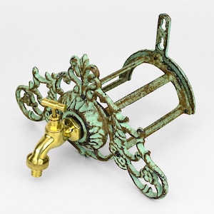 Puede incluir: Grifo de estilo antiguo con boquilla de latón y base de hierro fundido verde turquesa desgastado. El grifo presenta adornos decorativos y un diseño clásico, perfecto para jardín o exterior.