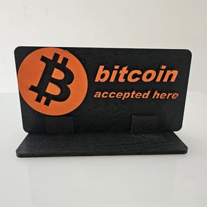May include: Black wooden sign with a stand, featuring an orange bitcoin symbol and the text "bitcoin accepted here".