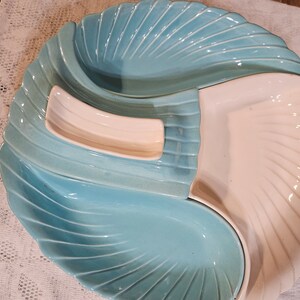 May include: A blue and white ceramic serving dish with three sections. The dish is shaped like a seashell and has a scalloped edge.
