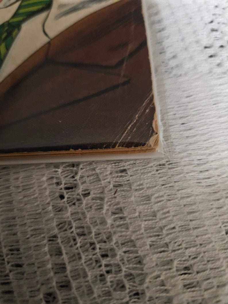 K&ouml;nnte beinhalten: Nahaufnahme der unteren Kante eines Buches mit braunem Einband und wei&szlig;em R&uuml;cken. Das Buch ist leicht abgenutzt und hat ein paar Falten.