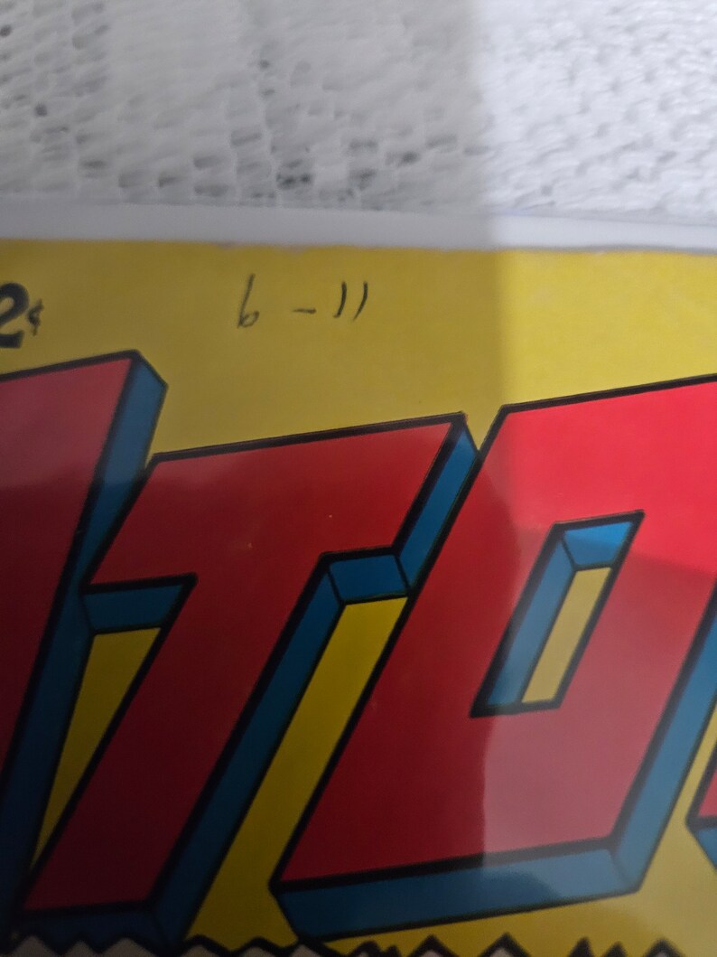 K&ouml;nnte beinhalten: Ein rotes und gelbes Comic-Cover mit dem Wort "ATOM" in gro&szlig;en, fetten, blau umrandeten Buchstaben. Das Cover hat eine handschriftliche Nummer "6-11" in der oberen rechten Ecke.