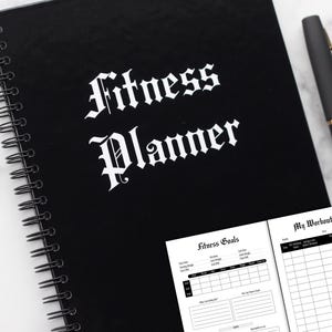 May include: Black spiral bound fitness planner with the words "Fitness Planner" in white gothic font on the front cover. The planner has two sections: "Fitness Goals" and "My Workout Log".