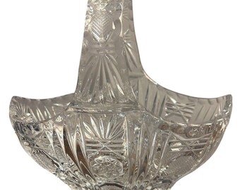 May include: A clear crystal basket with a cut glass design. The basket has a handle and is perfect for serving fruit or other small items.