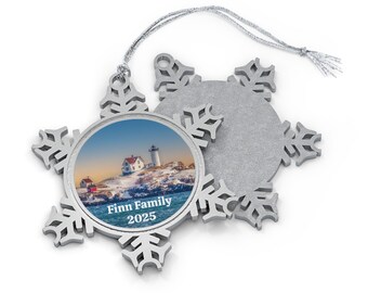 May include: Silver snowflake Christmas ornament with a photo of a lighthouse and the text "Finn Family 2025".