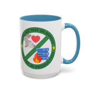 Può includere: Una tazza in ceramica bianca con bordo e manico blu. La tazza presenta un cerchio verde con un cuore rosso, un coniglio bianco e un server con fiamme. Il testo attorno al cerchio recita "Non testiamo sugli animali. Testiamo in produzione."
