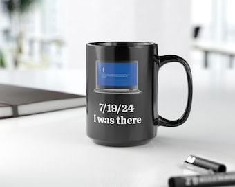 May include: Black coffee mug featuring a white image of a laptop screen displaying the blue screen of death. The text "7/19/24 I was there" is printed below the image.
