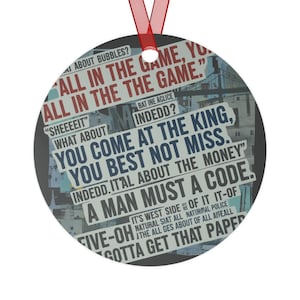 May include: Round metal Christmas ornament with a red ribbon. The ornament features text from a newspaper, including phrases like "All in the game" and "You come at the king." The background shows a cityscape.