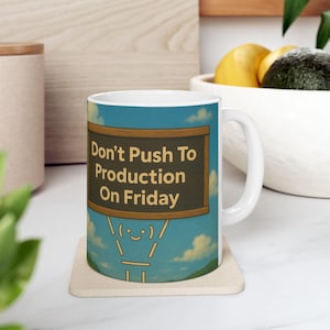Könnte beinhalten: Weiße Keramiktasse mit einem Design aus blauem Himmel und Wolken. Die Tasse zeigt eine Strichmännchenfigur, die eine Tafel mit dem Text "Don't Push To Production On Friday" hält.