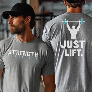 May include: Two gray t-shirts with white text. The shirt on the left says "STRENGTH REDEFINED". The shirt on the right says "JUST LIFT." with a silhouette of a person lifting a barbell.