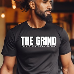 Puede incluir: Camiseta negra con texto blanco que dice "THE GRIND DELIVERS WHAT DREAMS PROMISE".