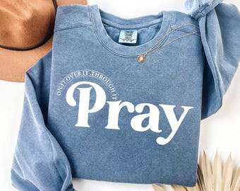 May include: A blue sweatshirt with the text "Pray On It. Over It. Through It." in white lettering.