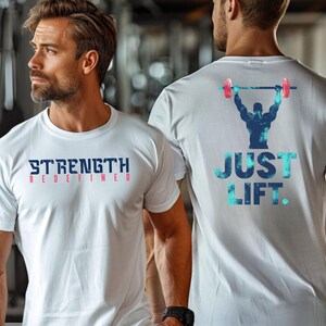 May include: Two white t-shirts with a fitness theme. One shirt says "Strength Redefined" in blue and red lettering. The other shirt says "Just Lift" in blue and teal lettering with a silhouette of a weightlifter in the center.