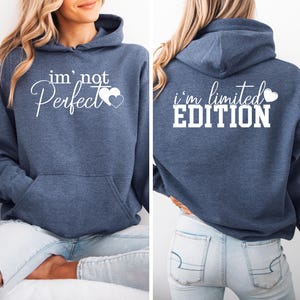 May include: A navy blue hoodie with a white graphic on the front that says "i'm not perfect" with two hearts. The back of the hoodie has a white graphic that says "i'm limited EDITION" with a heart.