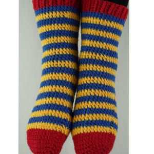 Puede incluir: Un par de calcetines tejidos a crochet con rayas amarillas, azules y rojas. Los calcetines están hechos con un punto texturizado.