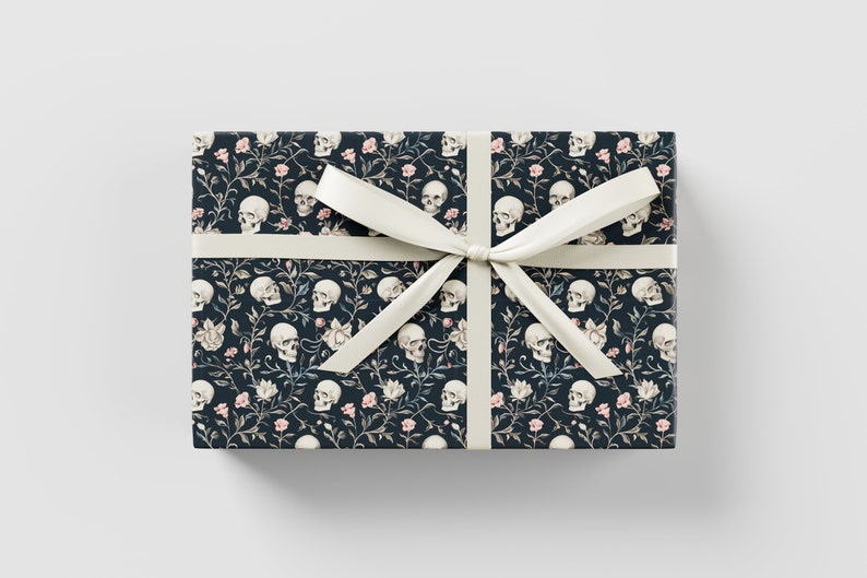 May include: Dark blue gift wrap with a white ribbon. The wrap features a repeating pattern of white skulls and pink flowers.