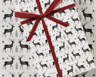 May include: A wrapped gift with a festive pattern of black deer, stars, and trees on a white background. The gift is tied with a wide, dark red velvet ribbon. Perfect for Christmas or winter holidays.
